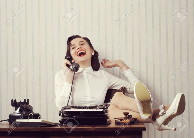 21510658-Cheerful-woman-talking-on-phone-at-desk-Stock-Photo-typewriter